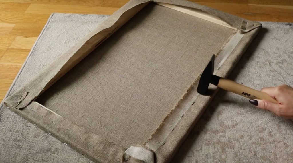 hammering the staples in a canvas